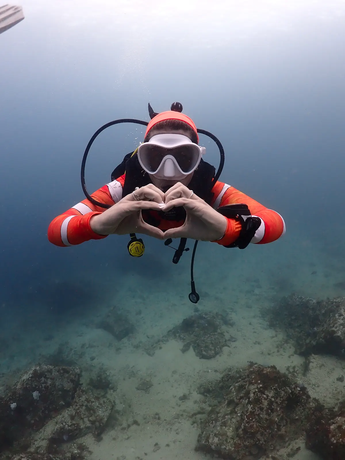 Candidato a Dive Master haciendo un corazón con las manos bajo el agua