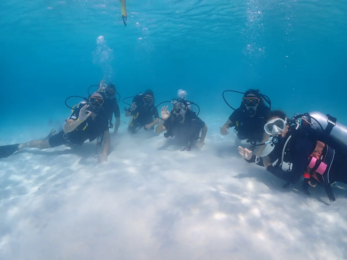 Alumnos de Open Water practicando habilidades sobre el fondo de arena