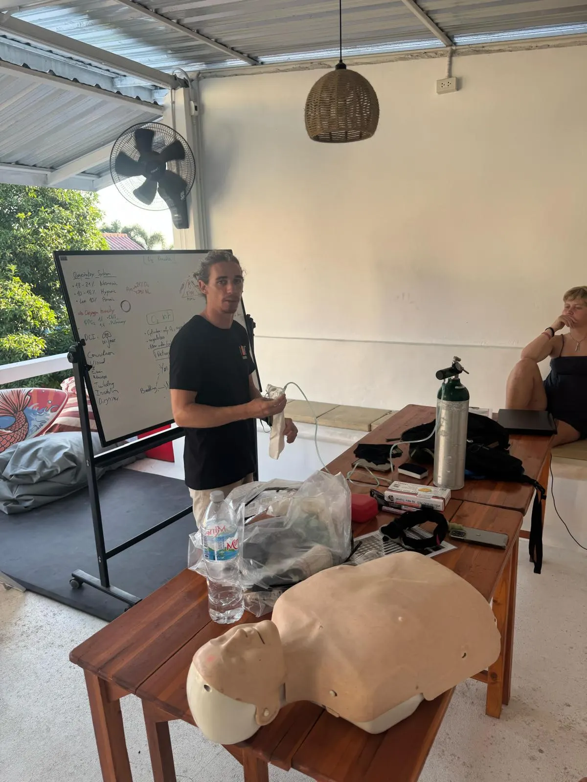Instructor enseñando la teoría de primeros auxilios y O2 con el maniquí de RCP y el kit de oxígeno