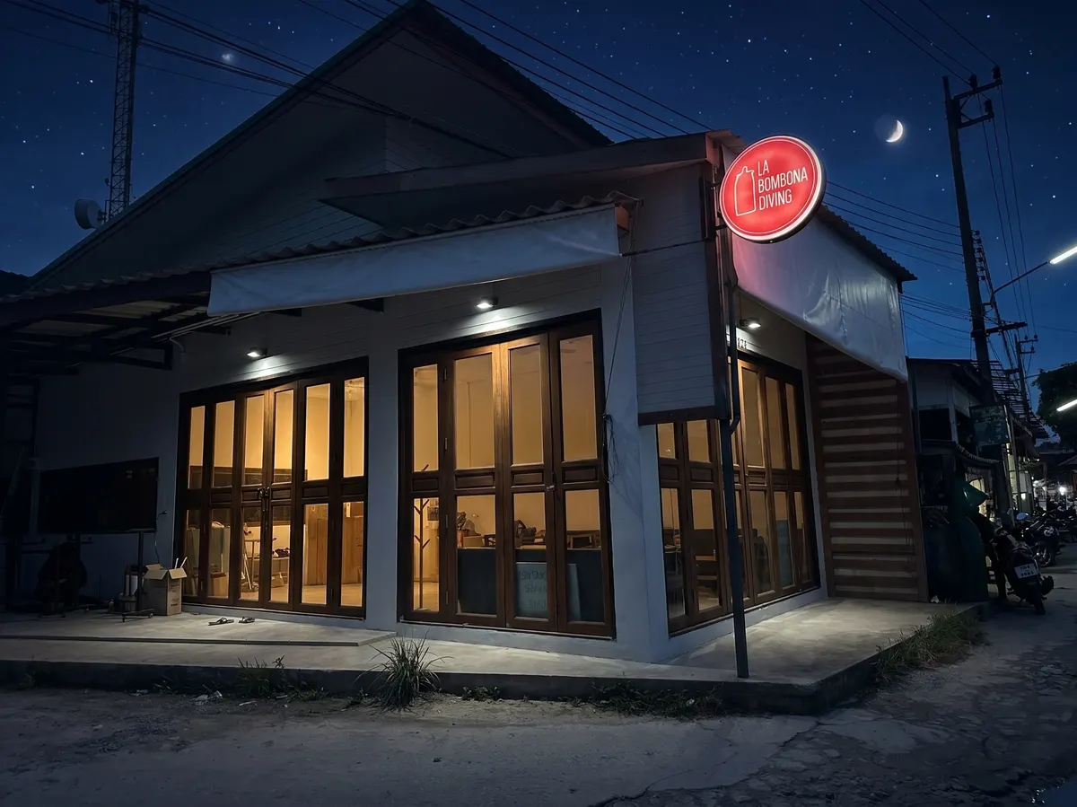 The La Bombona Diving dive centre lit up at night under a crescent moon