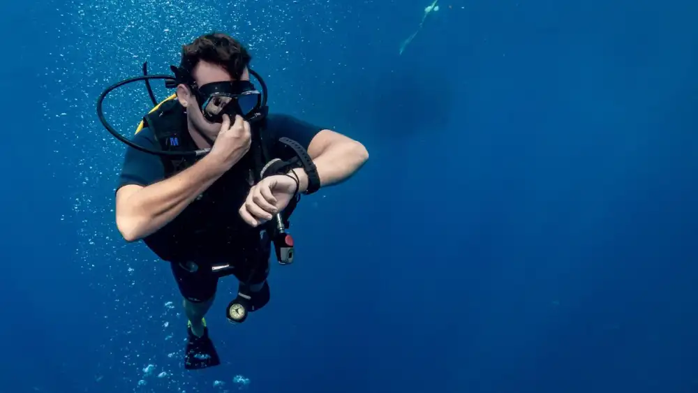 A diver underwater pinching their nose to signal that they are equalising their ears