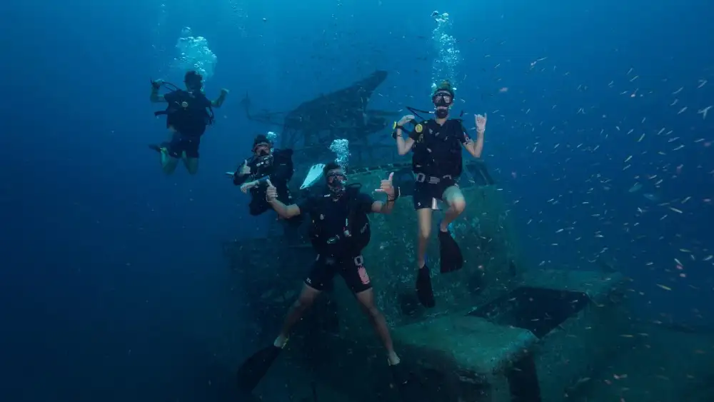 A divemaster guiding a deep dive along a pinnacle, divers following in the blue behind