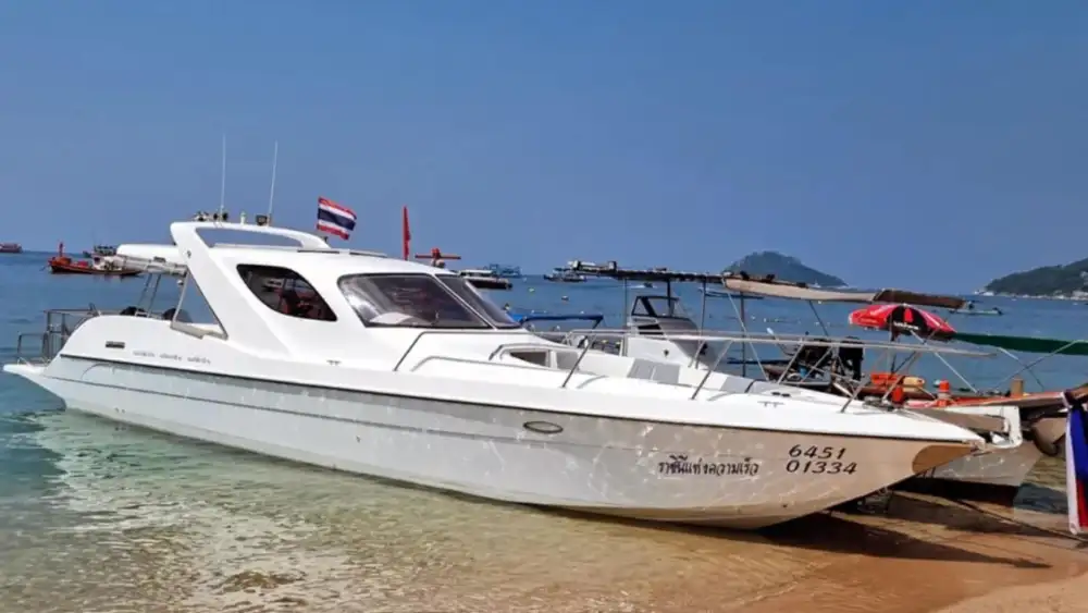 A tour boat anchored over a shallow reef in calm, clear water at one of Koh Tao's snorkelling bays