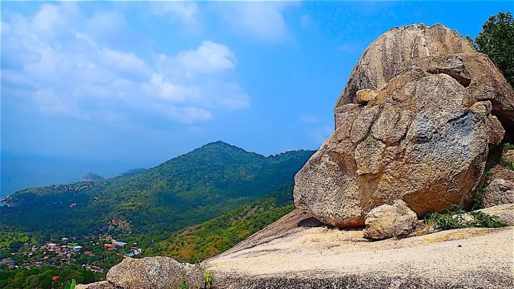 A quiet sandy cove on Koh Tao reached on foot, with granite boulders and clear shallow water