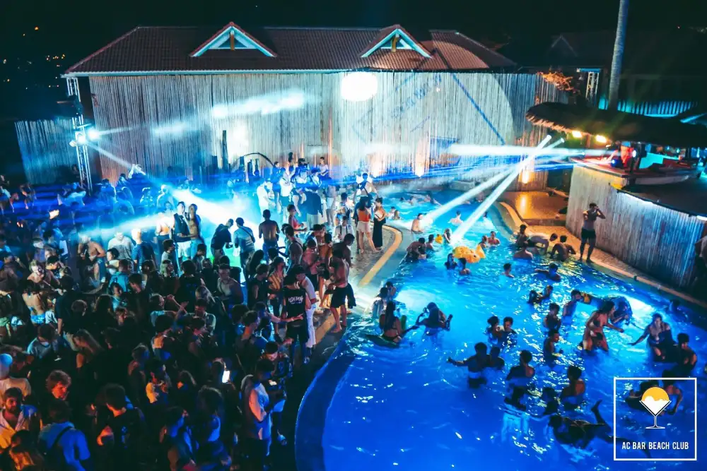 Pool party at AC Bar Beach Club on Sairee Beach, Koh Tao, with people in and around the pool at sunset