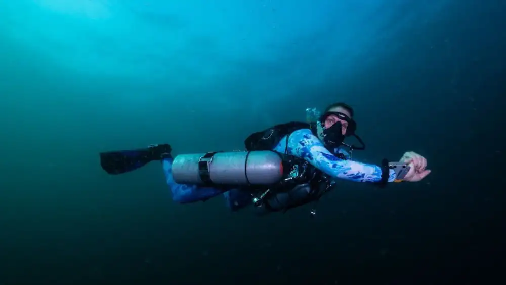 Underwater view of a sidemount configuration: two tanks clipped along the diver's sides with the regulator hoses routed close to the body