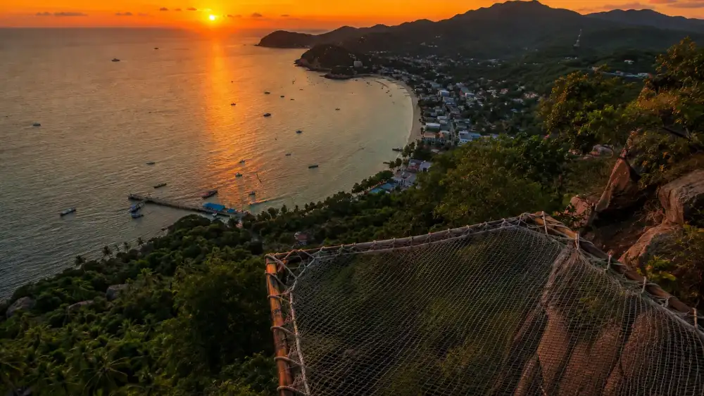 Sunset viewpoint (High Rock): net beds suspended at the cliff edge with Sairee Beach and Mae Haad far below