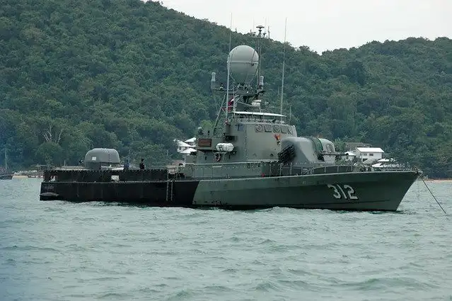 The Royal Thai Navy fast attack craft 312 at anchor in front of a forested coastline, before being sunk as an artificial reef