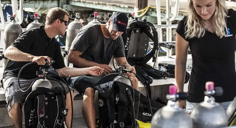 A diver rinsing scuba equipment in a fresh-water tank after a dive