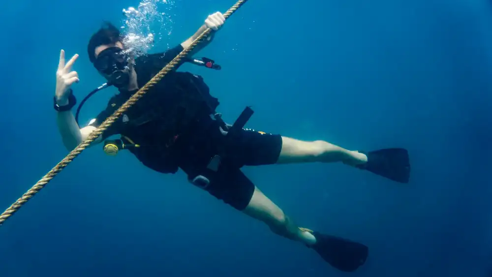 A beginner diver underwater in Koh Tao, guided by an instructor over a shallow reef