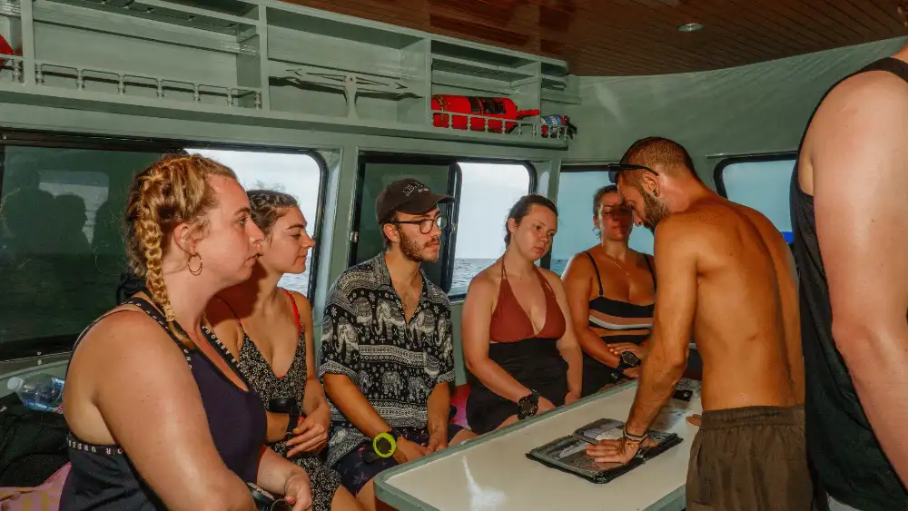 A dive instructor guiding a group of students through skills practice in shallow water