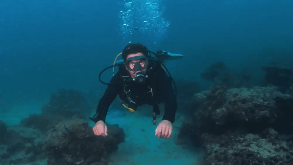 A certified dive instructor in full scuba gear on a Koh Tao dive boat, ready to lead a dive