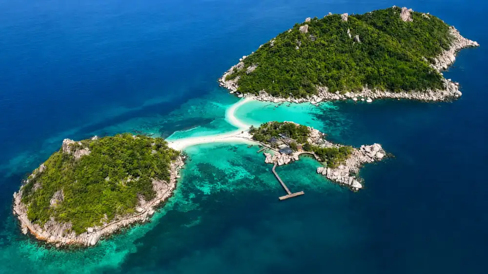 A viewpoint over one of Koh Tao's bays, with white sand, granite boulders and turquoise water below
