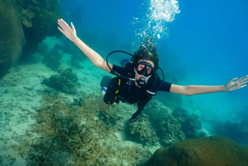 A beginner scuba diver swimming over the reef in clear water off Koh Tao