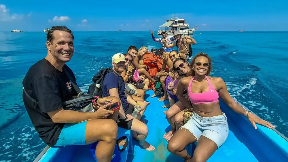 Scuba divers descending over a shallow reef in the clear water of Koh Tao