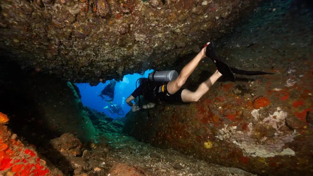 A beginner diver in shallow water learning to breathe calmly through the regulator, instructor close by