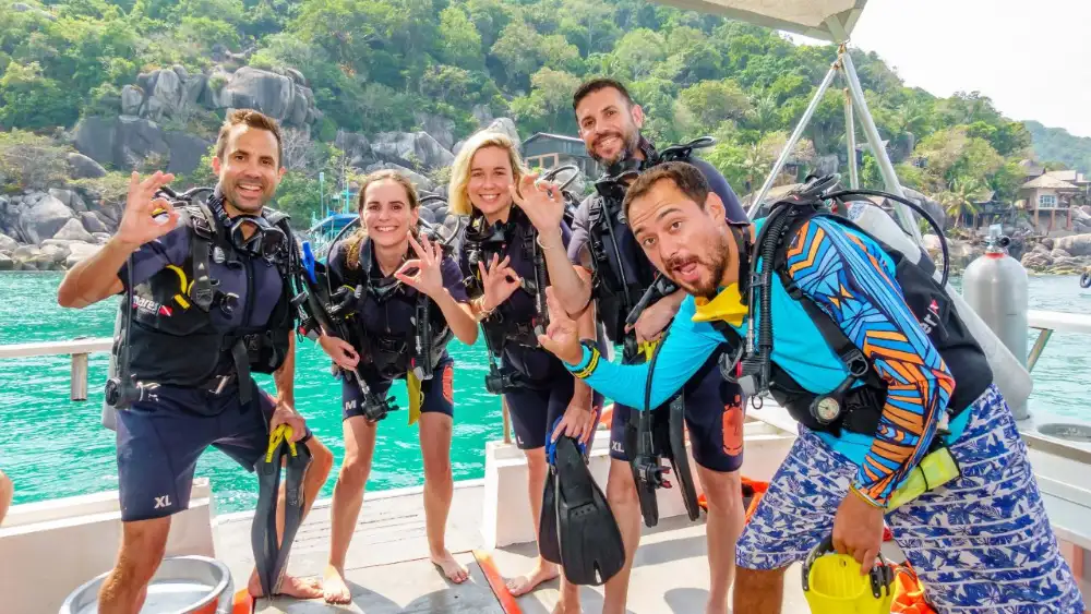 Divemaster trainees descending along a reef in Koh Tao's clear water during a training dive