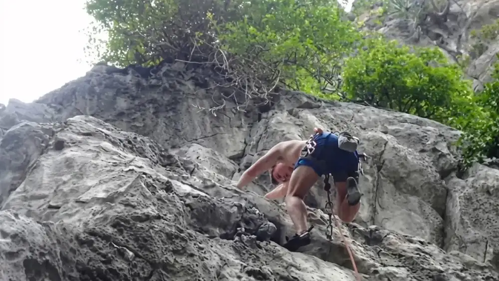 A climber roped up on one of Koh Tao's granite boulders during a guided rock climbing session