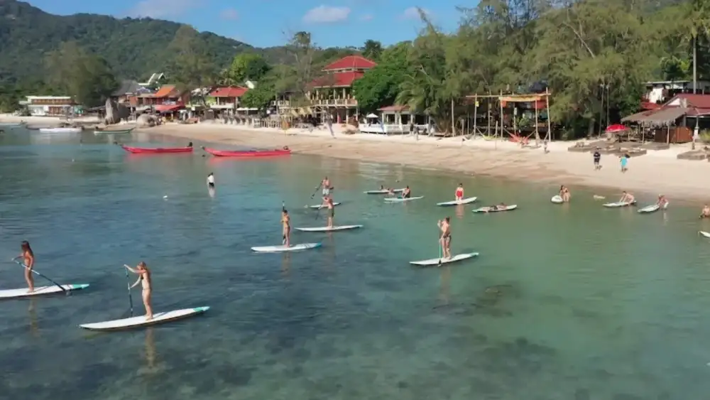 A stand-up paddleboarder on the calm water in front of Maya Beach Club, Mae Haad, Koh Tao