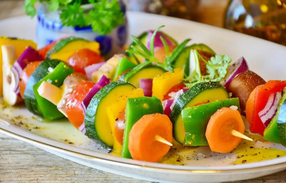 A spread of fresh vegetarian dishes — salads, vegetables and dips — laid out on a wooden table
